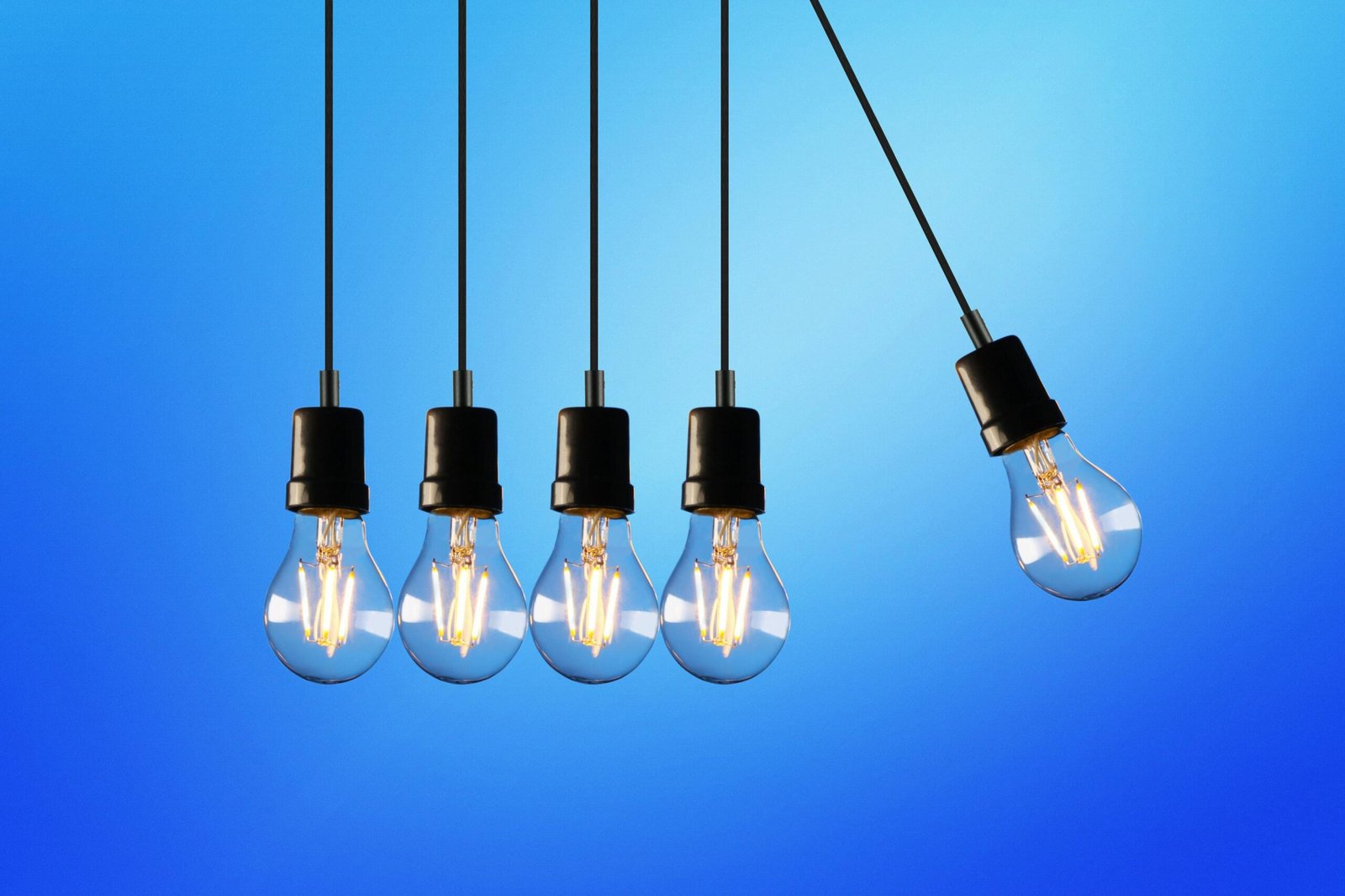 Hanging Edison-style light bulbs against a vibrant blue backdrop, showcasing energy and innovation.